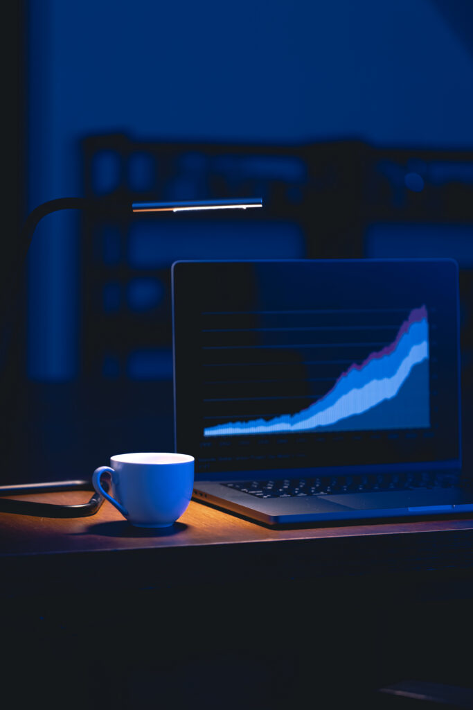 computer in a dark room with graphs on the screen.